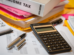 Image of calculator, uncapped pen, and tax filing documents