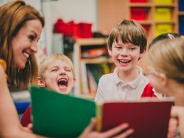 photo of a woman reading a book to laughing children