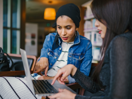 photo of two woman looking at a laptop and pointing at the screen