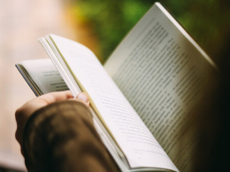 Image of hands thumbing through an open book