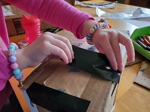 photo of child taping cardboard box