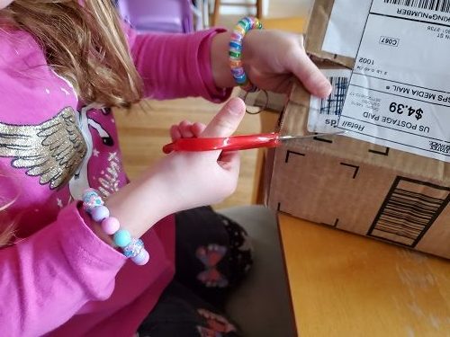 photo of child cutting cardboard box