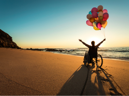 photo of a person on a beach in a wheelchair with balloons